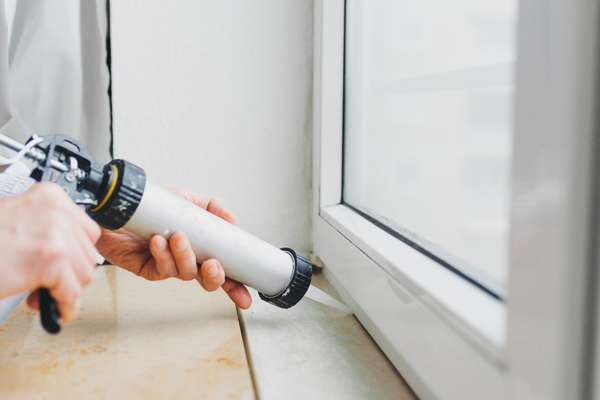 https://www.wilcox-energy.com/wp-content/uploads/2017/03/image-of-a-man-caulking-window-to-prevent-air-leaks.jpg