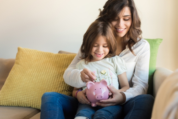 mom and daughter putting money on coin bank depicting budget friendly home heating