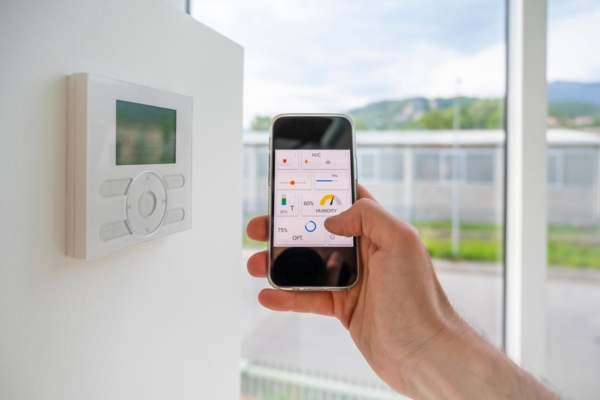 homeowner setting home thermostat using smart phone