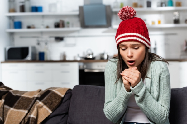 Cold woman in warm hat blowing on clenched hands depicting reduced heating efficiency