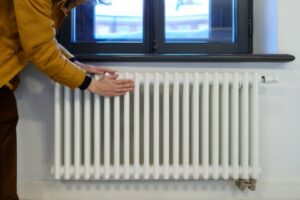 Woman warming hands near heating radiator