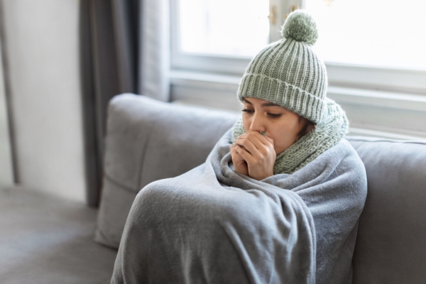 Young Woman Feeling Cold At Home due to HVAC neglect